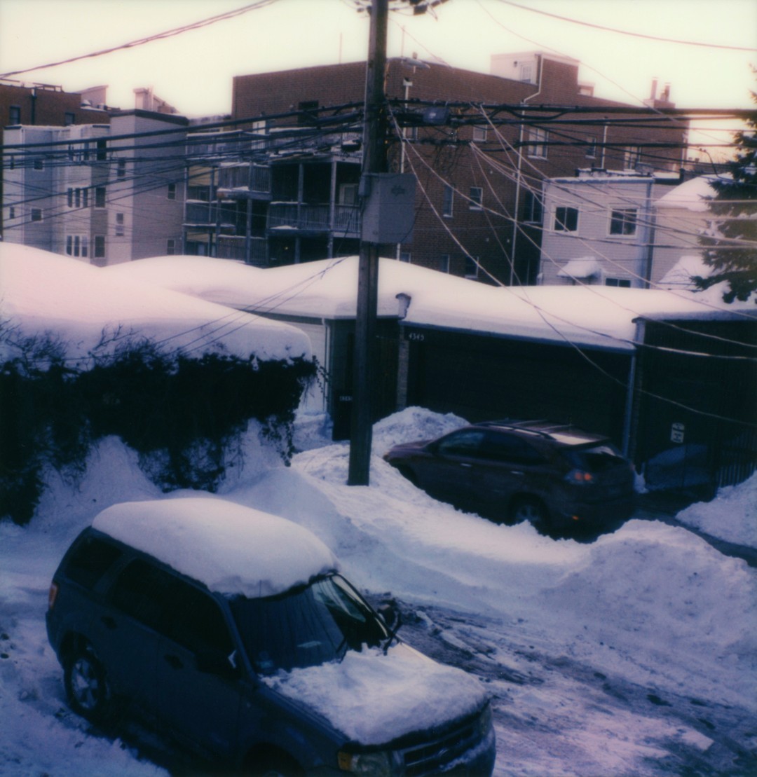 An elevated perspective of a snowy Chicago alleyway with a truck in the lower third.