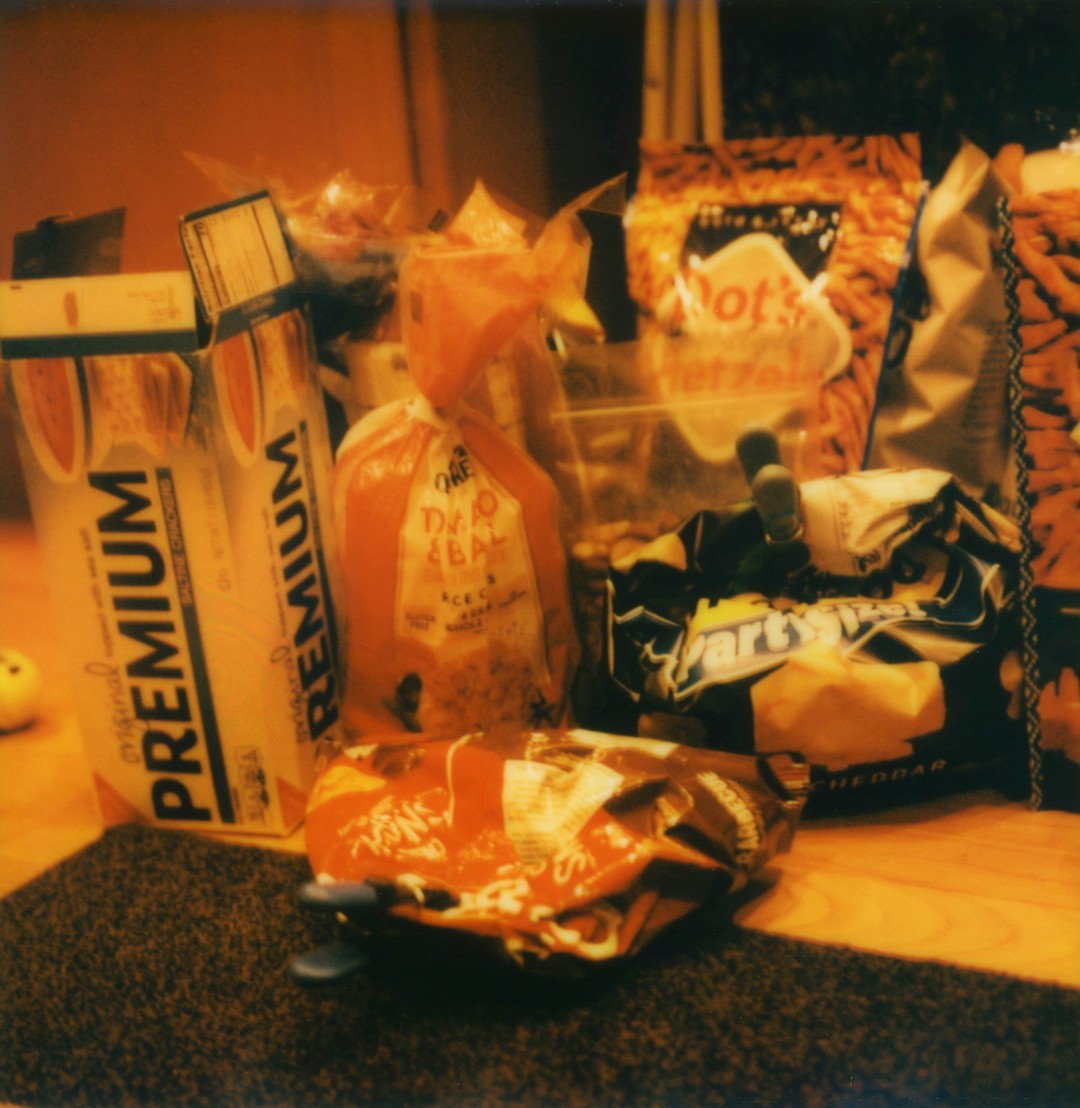 A box of Saltines, a bag of chips, a bag of pop corn, rice cakes and pretzels.