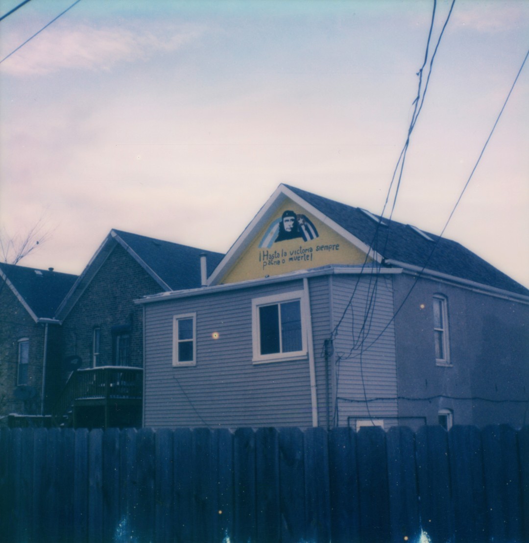 A house behind a fence with the words “¡Hasta la victoria siempre patria o muerte!” painted on it with a portrait of Che Guevara