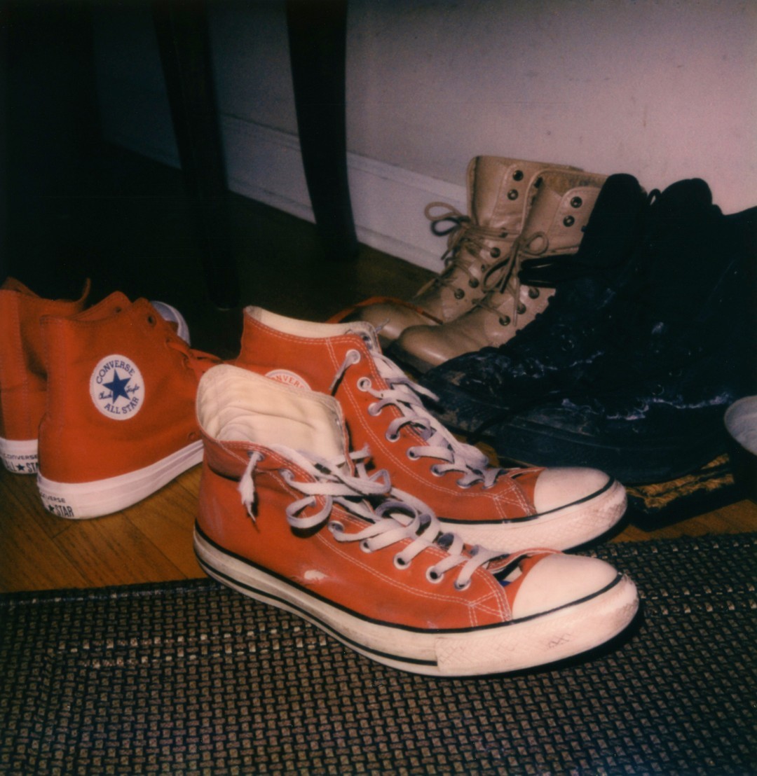 Two pairs of red converse shoes, and several other women's boots.