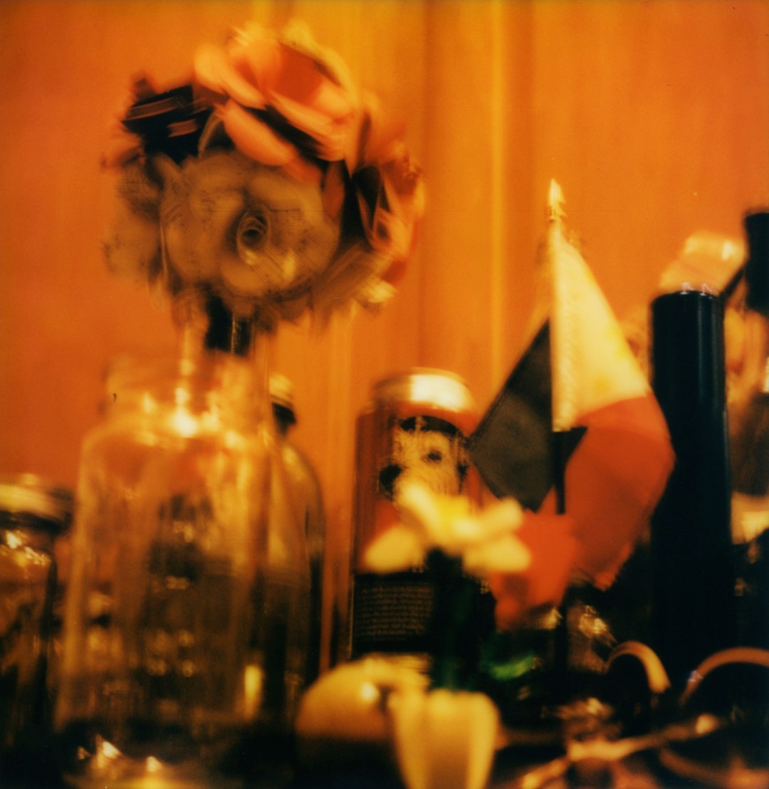 Bottles and flags on the top of a kitchen fridge.