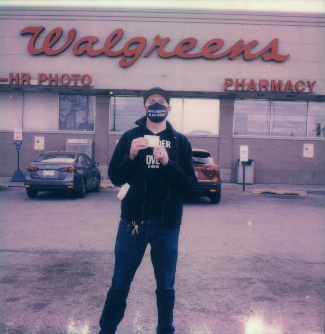 A man in all black holding a vaccination card