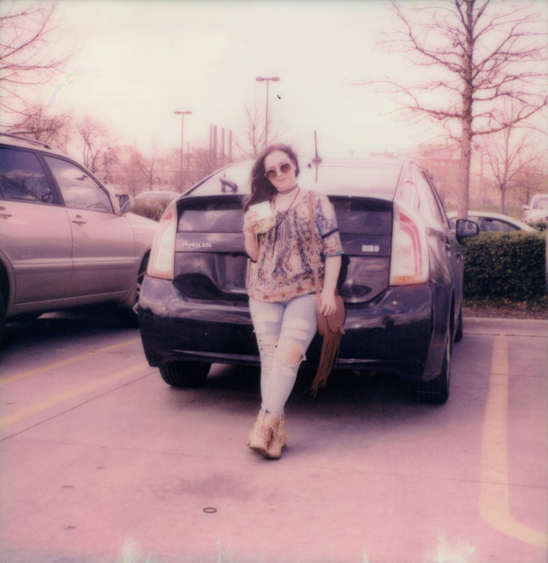 A woman leaning against the back of a Toyota Prius