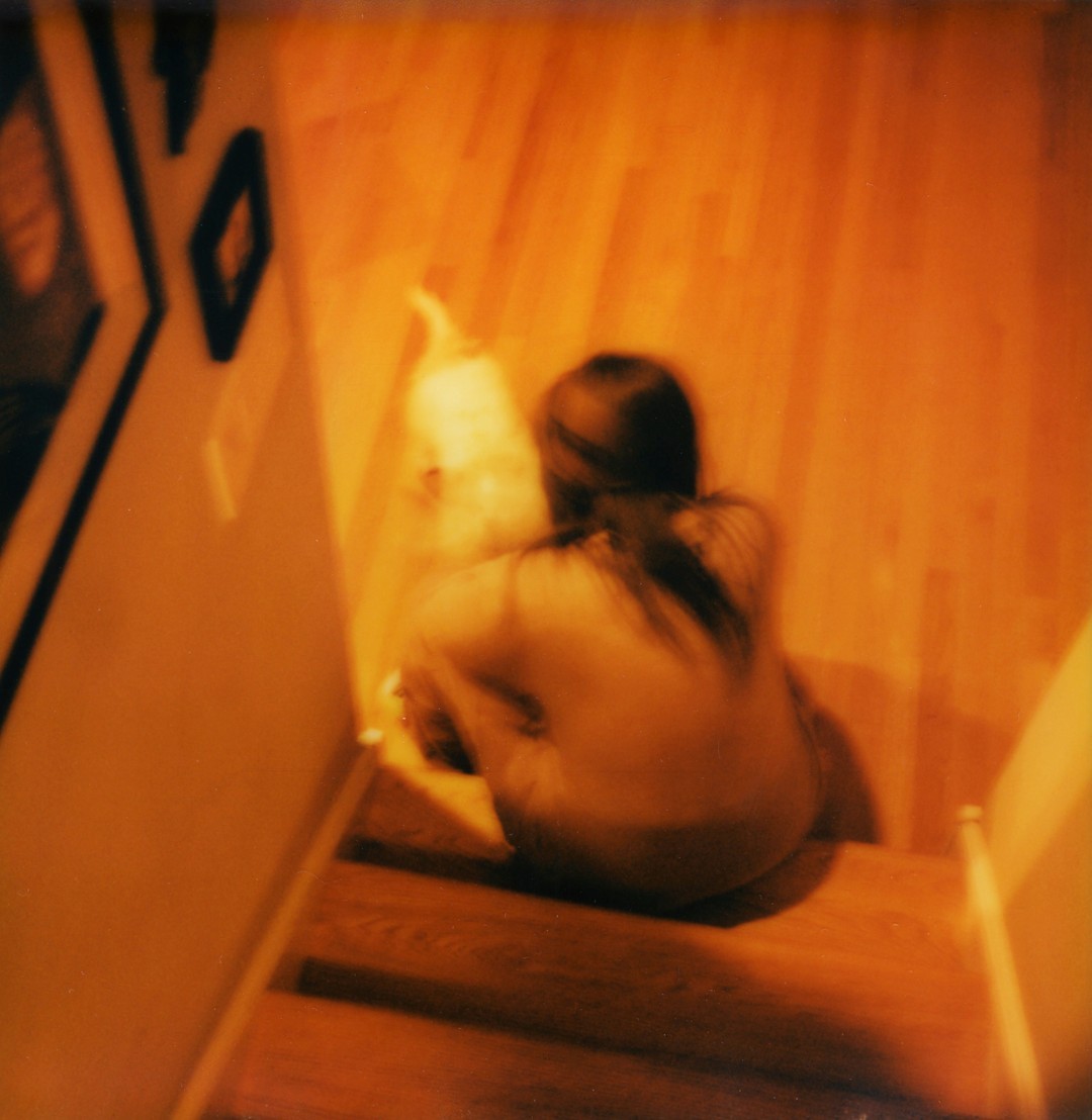 A woman sitting on a staircase with a dog in front of her.