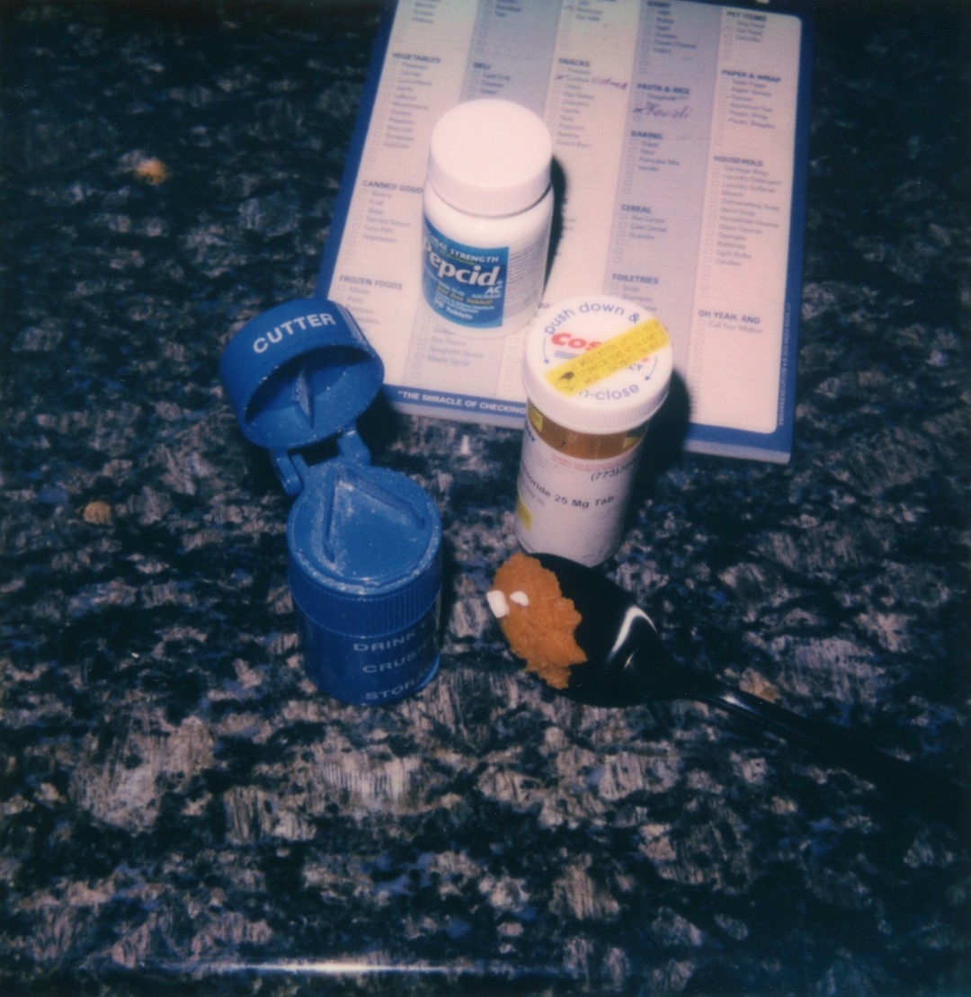 Two bottles of pills and a pill cutter on a kitchen counter.