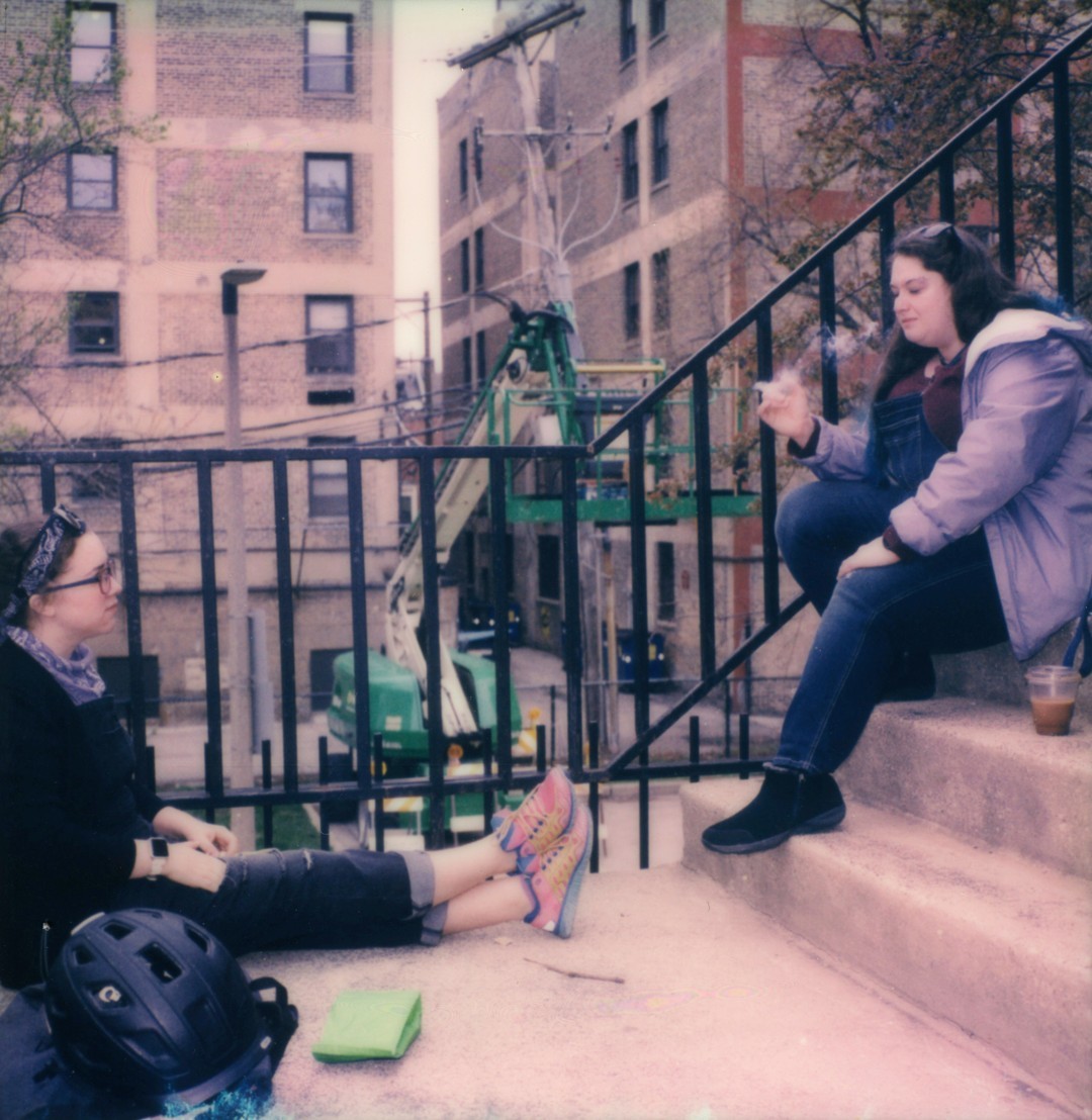 Two women sit on a concrete staircase